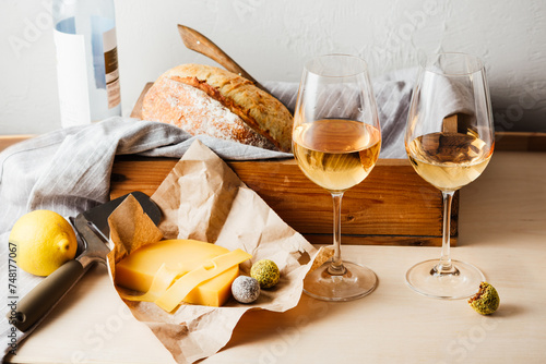 Two glasses of white wine, cheese, bread.