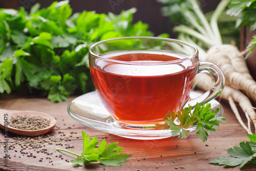 Parsley tea with fresh seeds, leaves, roots nearby on rustic wooden table, copy space, natural remedy for kidney, heart, menstrual, blood desease, healthy organic food concept