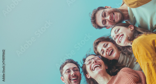 Six young friends look upwards and laugh wholeheartedly, against a clear blue sky, representing friendship and joy photo