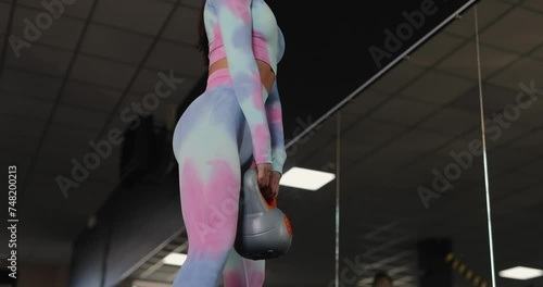 Woman doing squats with weight at the gym, pumping glutes photo