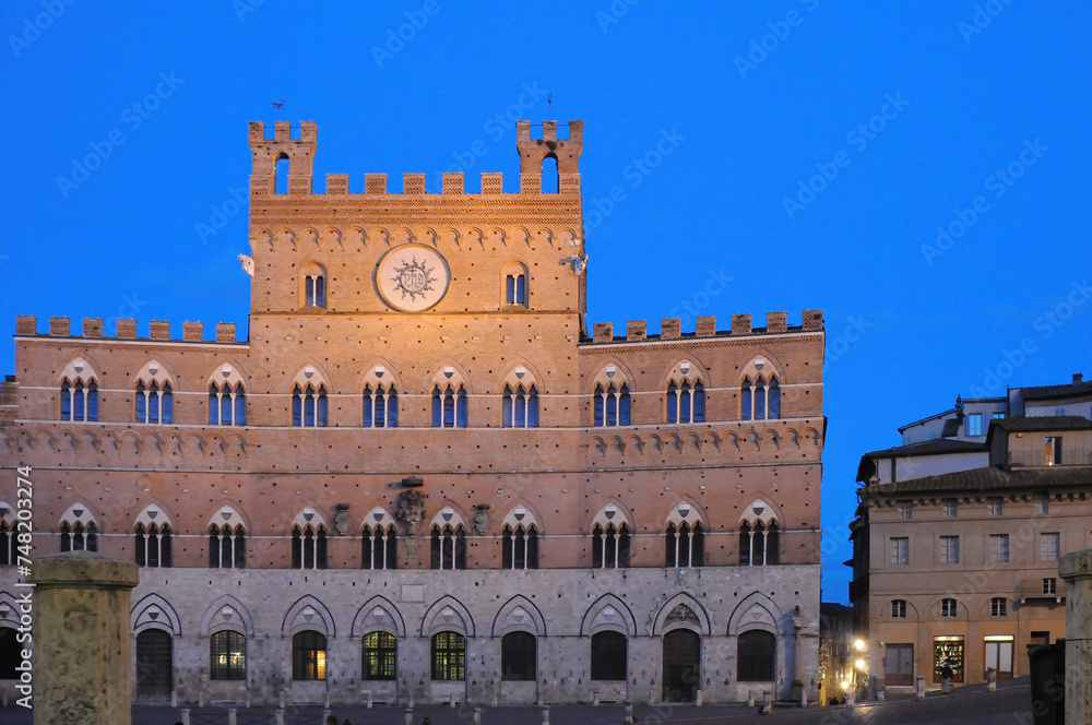 The gothic Palazzo Pubblico (city hall) in the golden hour with deep blue sky on the Piazza del Campo in Siena, Tuscany, Italy