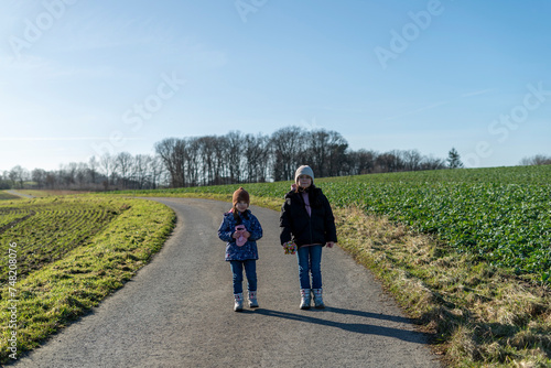 Two sisters walking on a country road in the countryside in spring