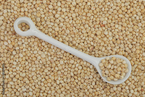 background of sorghum seeds with ceramic spoon. Top view. Flat lay.