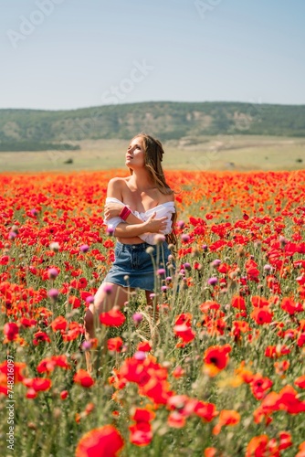Woman poppies field. Side view of a happy woman with long hair in a poppy field and enjoying the beauty of nature in a warm summer day.