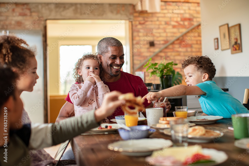 Mixed family having breakfast together at the kitchen table Mixed family having breakfast together at the kitchen table