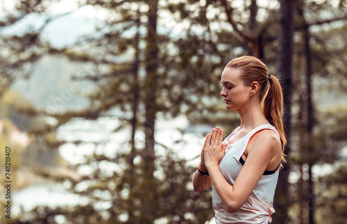 Woman practicing yoga in a peaceful field surrounded by trees photo