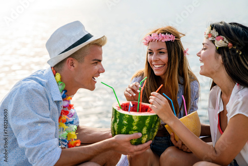 Happy young people having fun at beach party. Group of friends enjoying summer vacation.