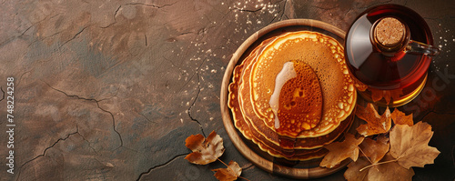 A bottle of maple syrup and a pancake on a brown background. Canadian specialty with sweet and sticky sauce. Top view space to copy. photo