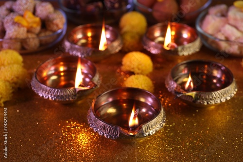 Diwali celebration. Diya lamps on shiny golden table, closeup