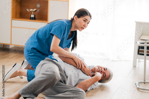 senior patient falling on the ground floor at home, Asian caregiver helping elderly older male from accident after doing physical therapy then rescued by attractive therapist nurse, health insurance