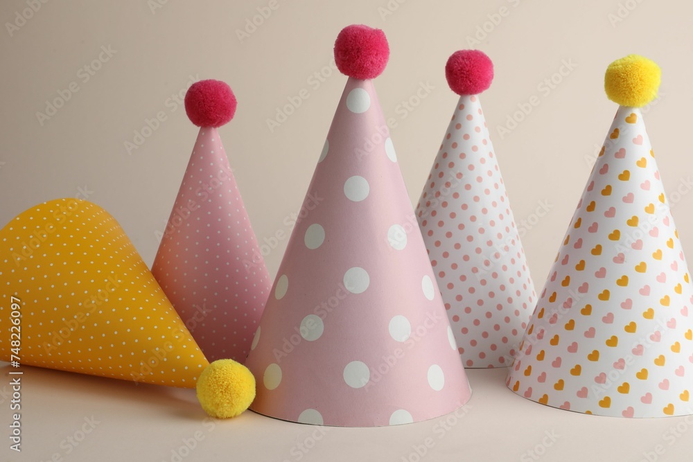 Beautiful party hats with pompoms on beige background Beautiful party hats with pompoms on beige background