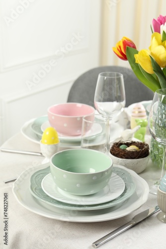 Easter celebration. Festive table setting with elegant dishware and painted eggs