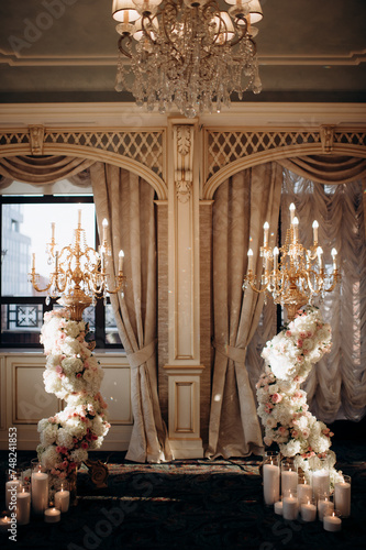 Wedding decoration with vintage crystal chandeliers with candles and white and pink flowers. Glass pendants in the form of balls. A light bulb in the shape of a candle.
