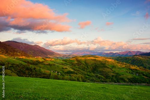 carpathian countryside scenery with grassy meadows and forested hills in evening light. mountainous rural landscape of transcarpathia, ukraine in spring © Pellinni