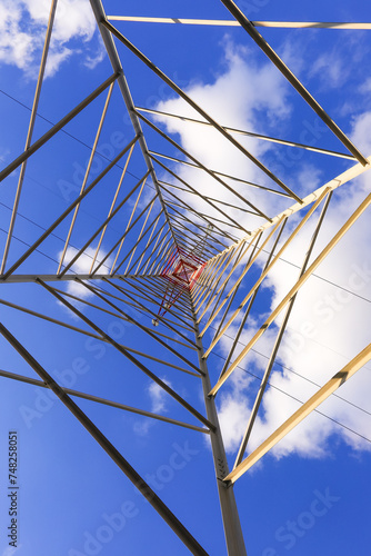 high pylon with high voltage cables for the transport of electricity and white clouds on the sky photo