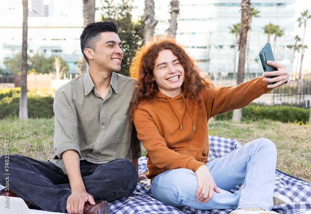 Smiling diverse students enjoying a picnic and taking a selfie Smiling diverse students enjoying a picnic and taking a selfie