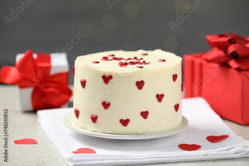 Bento cake with red cream hearts and gift boxes on grey table. St. Valentine's day surprise