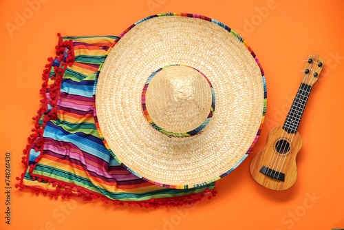 Mexican sombrero hat  guitar and colorful poncho on orange background  flat lay