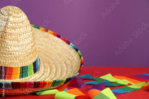 Mexican sombrero hat on red table, closeup. Space for text