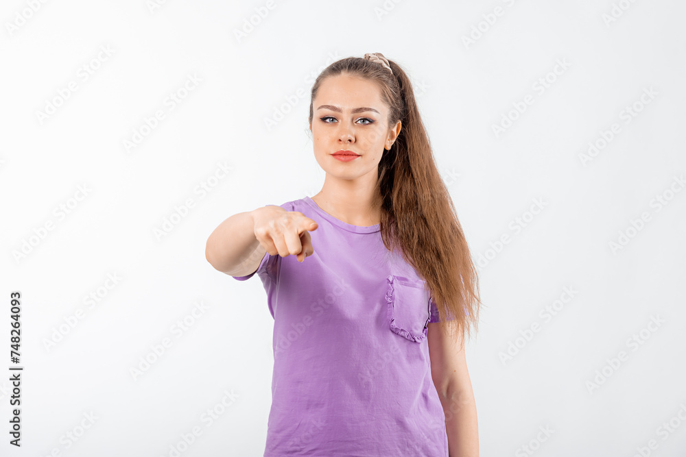 Angry young woman with long hair pointing index finger at camera and frowning with disappointed face, blaming all her failures on you, standing over white background Angry young woman with long hair pointing index finger at camera and frowning with disappointed face, blaming all her failures on you, standing over white background