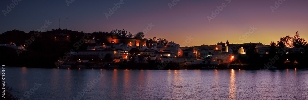 Alcoutim un pequeño pueblo del Algarve en Portugal. Alcoutim al anochecer a orillas del río Guadiana. Casas blancas con las últimas luces del día y las farolas encendidas.