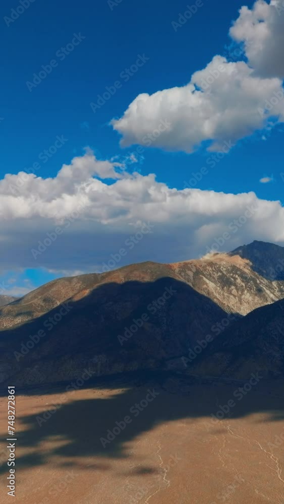 White soft cumulus clouds soaring over the beautiful mountains. Cloudscape throwing shadows on the rocks. Fantastic azure skies at backdrop. Vertical video. White soft cumulus clouds soaring over the beautiful mountains. Cloudscape throwing shadows on the rocks. Fantastic azure skies at backdrop. Vertical video.