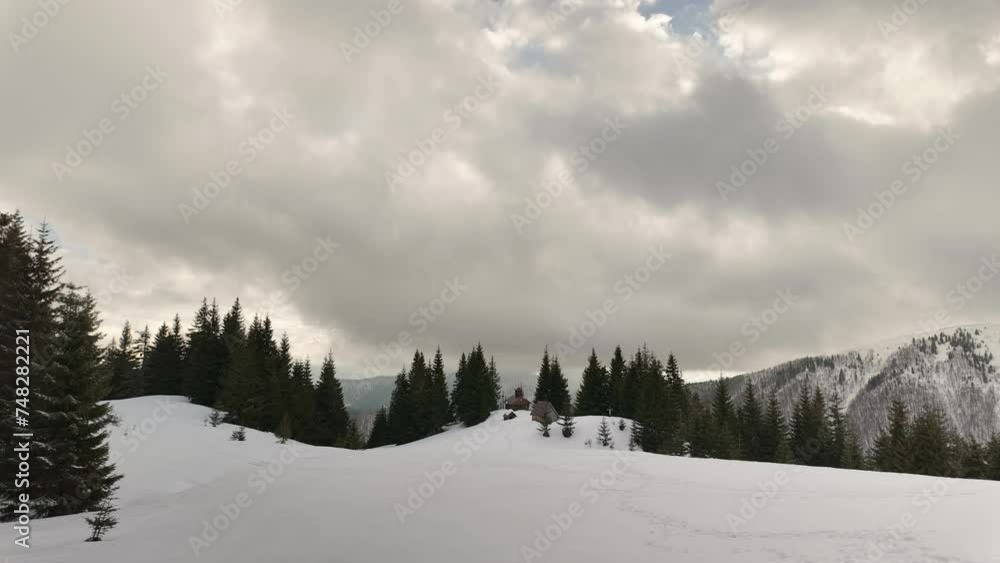 The Carpathians in winter in Ukraine are covered with snow, an Orthodox church is visible from the height of the mountain, the rapid movement of clouds is symbolic The Carpathians in winter in Ukraine are covered with snow, an Orthodox church is visible from the height of the mountain, the rapid movement of clouds is symbolic