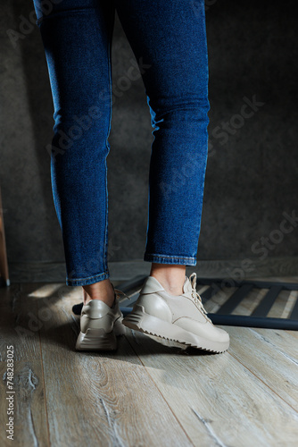 Beige women's sneakers. Collection of women's leather shoes. Female legs in leather beige casual sneakers. Stylish women's sneakers.