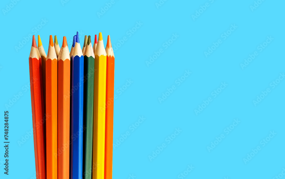 Fototapeta premium Colored pencils grouped together on a blue background with copy space. 