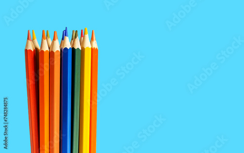 Colored pencils grouped together on a blue background with copy space. 