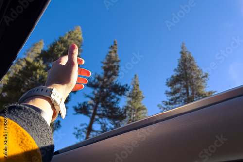 Принти на полотні Female hand reaching out the air through the open sunroof in the car