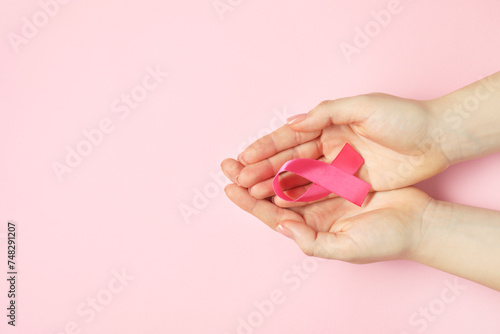 Breast cancer awareness. Woman with pink ribbon on color background, top view. Space for text