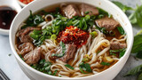 Beef Pho Noodle Soup with Fresh Herbs and Chili