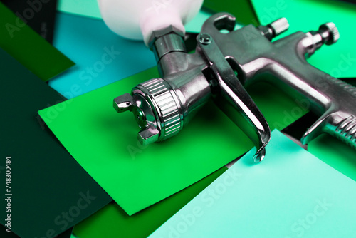 a paint spray gun at work at the workplace in the workshop. Paint samples.