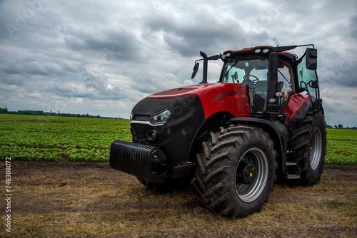 red powerful tractor near a field of young beets  agriculture  preparation for the season