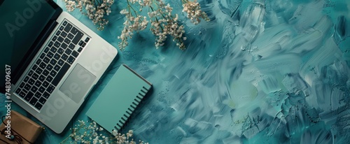 an empty notebook on a blue surface and a laptop on it