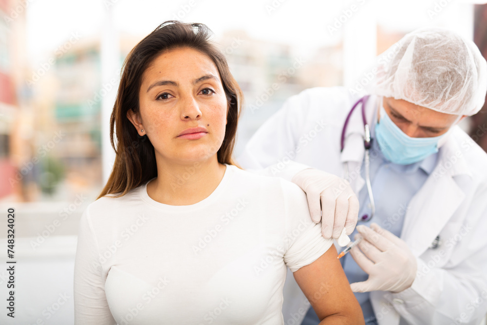 Fototapeta premium Health care concept, doctor in protective face mask vaccinates woman against coronavirus at vaccination center