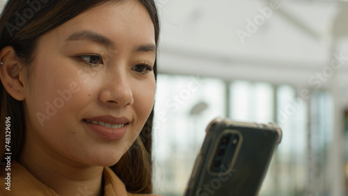 Close up smiling Asian chinese japanese woman portrait multiracial girl businesswoman read social media smartphone screen use mobile phone in office korean ethnic female lady student chatting message