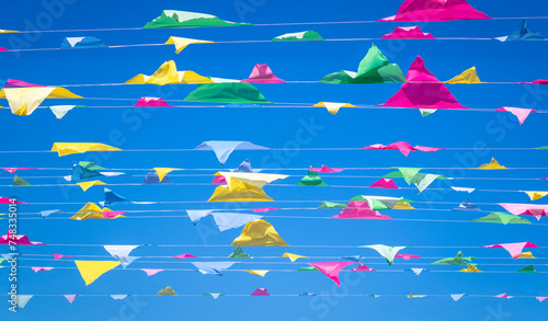 Rows of colorful bunting flags against a blue sky background. Bunting is a traditional decor, usually multi-coloured, decoration hung at parties, festivals, weddings and special events and occasions. photo