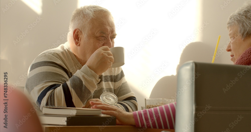 An elderly man enjoys a cup of tea or coffee in a cafe. Man surrounded by the aroma of freshly brewed coffee or the soothing fragrance of hot cup of tea. Casual conversation with woman wife or friend. An elderly man enjoys a cup of tea or coffee in a cafe. Man surrounded by the aroma of freshly brewed coffee or the soothing fragrance of hot cup of tea. Casual conversation with woman wife or friend.