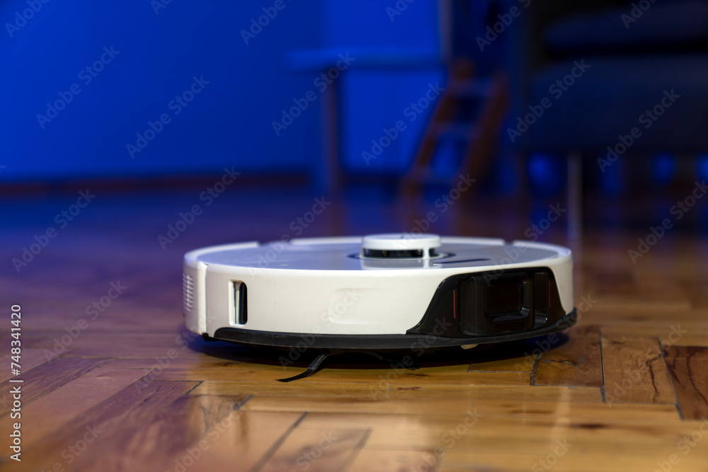 robot vacuum cleaner in modern smart home, robotic vacuum cleaner on wooden or laminate or parquet floor, cleaning dust on tile floors. Modern smart cleaning technology housekeeping. colorful back. robot vacuum cleaner in modern smart home, robotic vacuum cleaner on wooden or laminate or parquet floor, cleaning dust on tile floors. Modern smart cleaning technology housekeeping. colorful back.