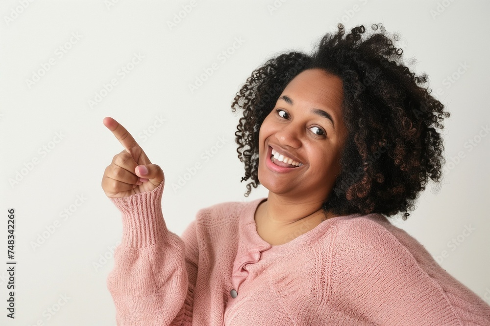 woman points with her finger to the to and smiles at the camera, background is plain woman points with her finger to the to and smiles at the camera, background is plain