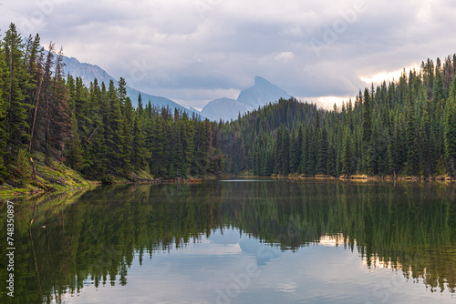 Moose Lake Loop Hike at Maligne Lake during fall, autumn September on cloudy day with reflection in clam water below stunning Canadian landscape scene. 