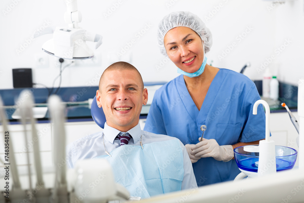 Portrait of satisfied man visiting dentist giving thumbs up in dental clinic