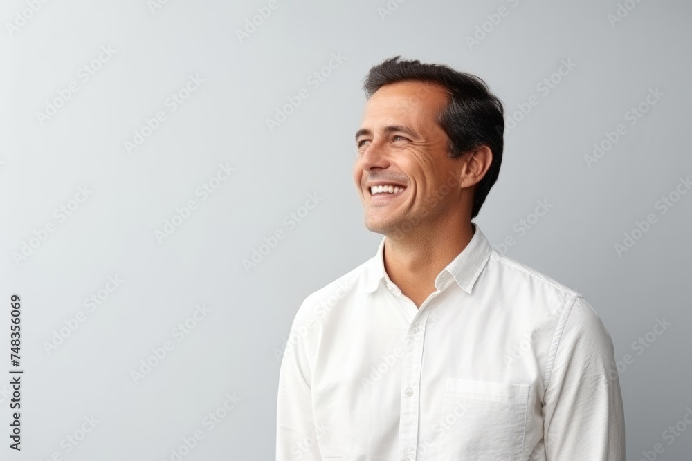 Portrait of a handsome young man laughing and looking up against grey background Portrait of a handsome young man laughing and looking up against grey background