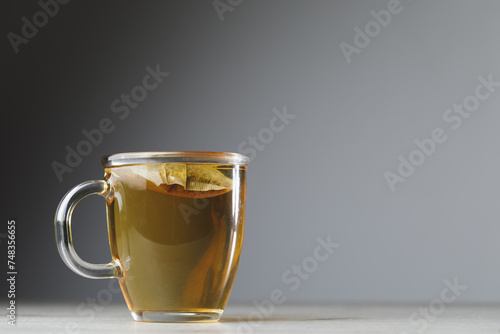 herbal tea in transparent cup on grey background with copy-space