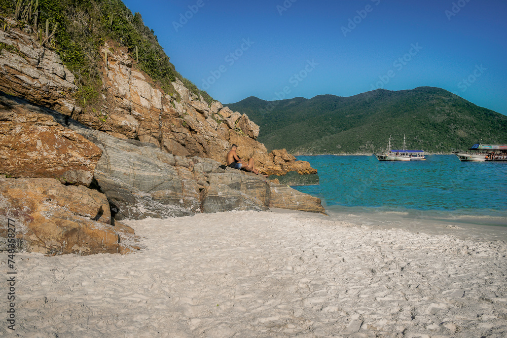 Fototapeta premium Beautiful beach with white sand, rocks and mountains around, located near the city of Cabo Frio, Rio de Janeiro.