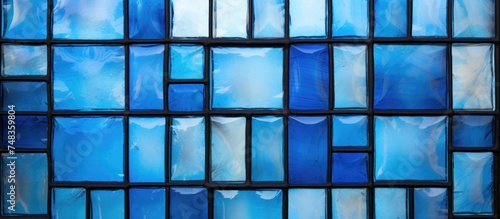 A detailed view of small blue stained glass squares arranged in an intricate pattern, part of a window in an English church. The vibrant shades of blue create a striking design against the light.