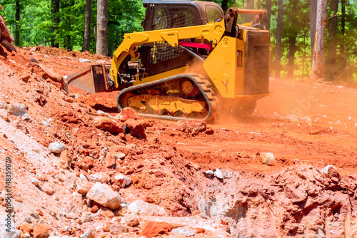 Excavator bucket skid steer loader unloading gravel at construction worksite photo