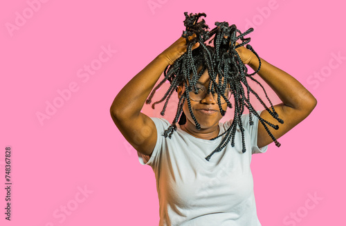 joven afro latina jugando con su pelo y sonriendo sobre fondo rosa photo